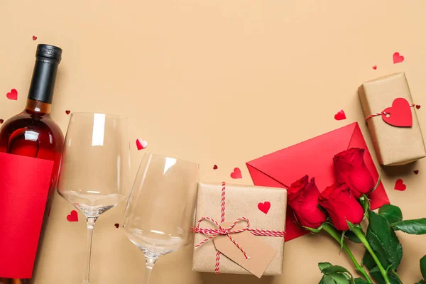 Envelope with roses, gifts and bottle of wine on beige background. Valentine\'s Day celebration
