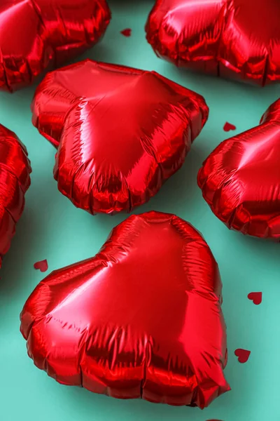 Red heart-shaped balloons on green background, closeup. Valentine\'s Day celebration