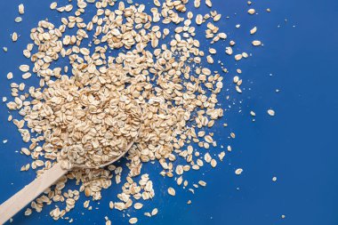 Mavi arka planda çiğ yulaf ezmeli kaşık