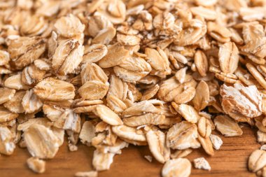 Tahta masadaki çiğ yulaf taneleri, yakın plan.