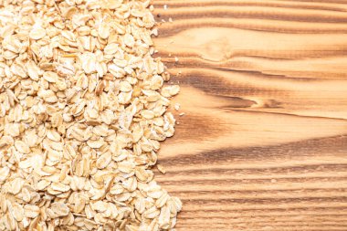 Ahşap arka planda bir yığın çiğ yulaf tanesi, yakın plan.