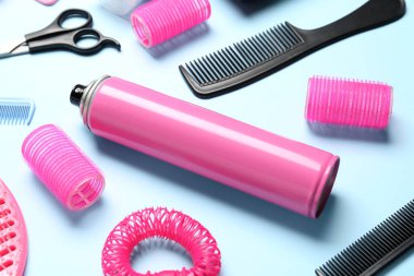 Saç spreyi ve saç bigudileri mavi arka planda, yakın plan.