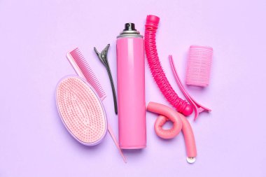 Saç spreyi, bigudiler ve leylak arkaplanda fırçalar.