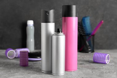 Koyu duvarın yanındaki masada saç spreyleri, yakın plan.