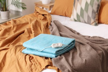 Katlanmış elektrikli ısıtma yastığı ve kontrol cihazı odada, yakın plan.