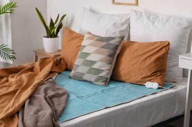 Yatak odasında elektrikli ısıtma yastığı olan bir yatak.