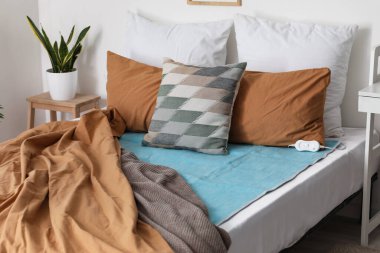 Yatak odasında yastıklı yatak ve elektrikli ısıtma yastığı.