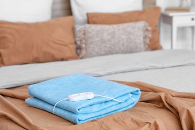 Katlanmış elektrikli ısıtma yastığı ve kontrol cihazı odada, yakın plan.