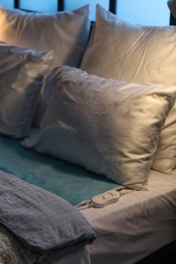 Karanlık odada elektrikli ısıtma yastığı ve kumandası var. Yakın plan.