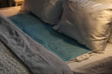 Karanlık odada elektrikli ısıtma yastığı ve kumandası var. Yakın plan.
