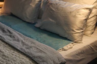 Karanlık odada elektrikli ısıtma yastığı ve kumandası var. Yakın plan.