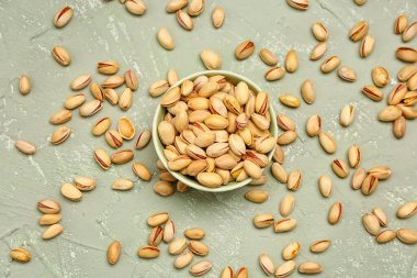 Gri arka planda lezzetli fıstıklı fındık ve kase.