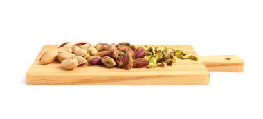 Beyaz arka planda soyulmamış, soyulmamış ve dilimlenmiş fıstıklı kesme tahtası.