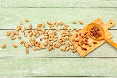 Tahta ve kaşık, yeşil ahşap arka planda fıstıklı.