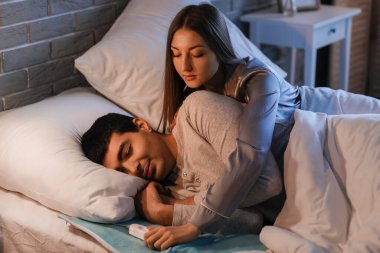 Genç çift geceleri yatak odasındaki elektrikli ısıtma yastığında uyuyor.