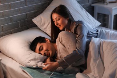 Geceleri yatak odasındaki elektrikli ısıtma yastığında yatan genç çift.