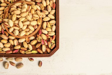 Tabak dolusu lezzetli fıstıklı beyaz masa.