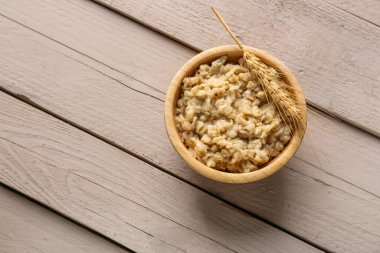 Lezzetli yulaf ezmesi ve ahşap arka planda buğday kulaklı kase.