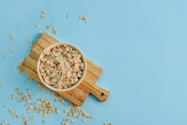 Mavi arka planda lezzetli yulaf ezmesi olan yemek ve kase.