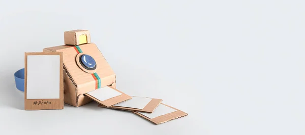 Cardboard photo camera with pictures on light background with space for text