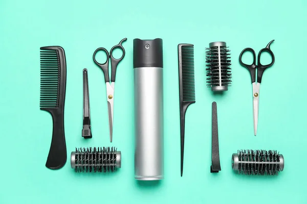 Hair spray with scissors, brushes and clips on green background