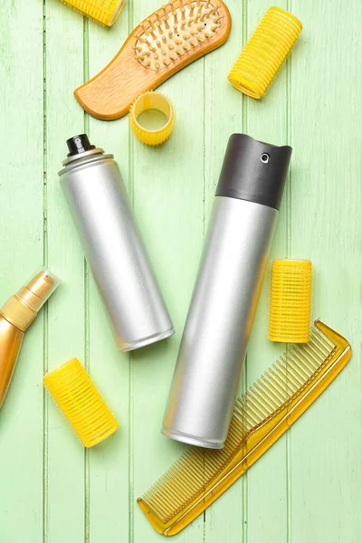 stock image Hair sprays with curlers and combs on green wooden background