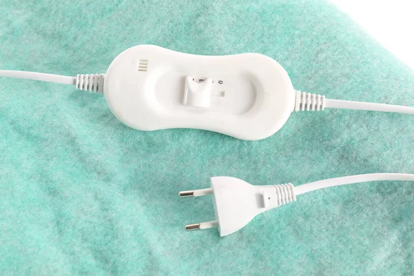 Electric heating pad with controller and plug on white background, closeup