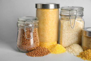 Beyaz arka planda izole edilmiş farklı tahıl gevrekleri olan cam kavanozlar.