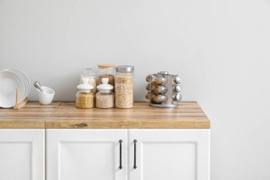 Farklı mısır gevrekleri ve baharatlarla dolu kavanozlar mutfaktaki ahşap masada.