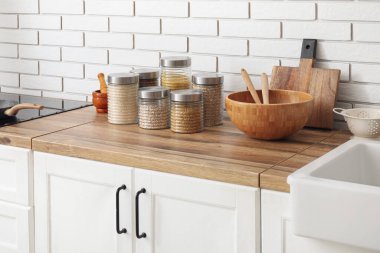 Mısır gevreği ve çatal bıçak dolu kavanozlar hafif tuğla duvarın yanındaki ahşap masada.