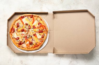 Açık arkaplanda lezzetli pizzalar olan karton kutu.