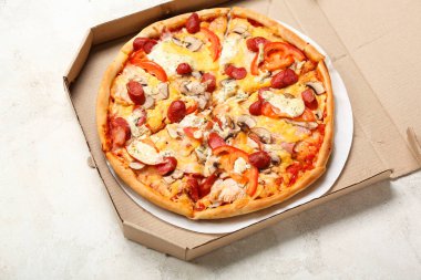 Açık arkaplanda lezzetli pizzalar olan karton kutu.