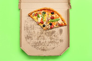 Yeşil arka planda lezzetli pizzalı mukavva kutu.