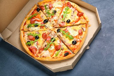 Koyu arkaplanda lezzetli pizzalar olan karton kutu.