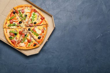 Koyu arkaplanda lezzetli pizzalar olan karton kutu.