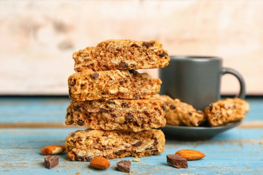 Lezzetli bisküvi, badem fıstığı, çikolata ve fincan mavi ahşap masada.