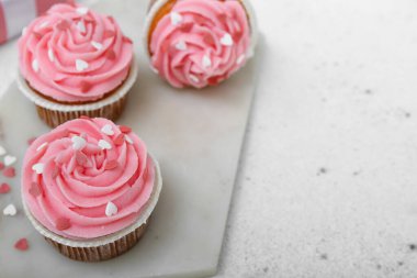 Beyaz arkaplanda Sevgililer Günü için lezzetli keklerle dolu bir pano, yakın plan.