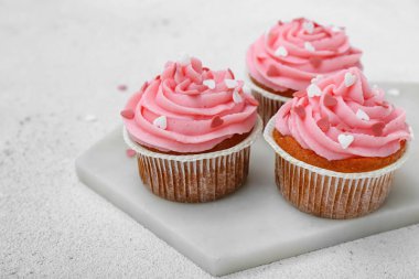 Beyaz arkaplanda Sevgililer Günü için lezzetli keklerle dolu bir pano, yakın plan.