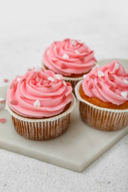 Beyaz arkaplanda Sevgililer Günü için lezzetli keklerle dolu bir pano, yakın plan.