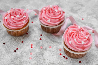 Arkaplanda Sevgililer Günü için kurdeleli ve kalpli lezzetli kekler.