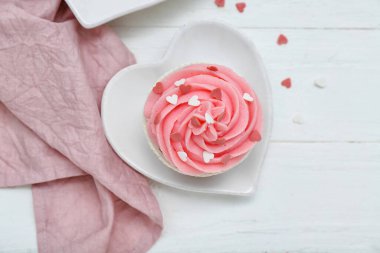 Beyaz ahşap arka planda Sevgililer Günü için lezzetli kek ve kalp tabağı.