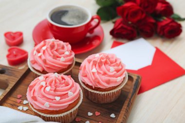 Tahta arka planda Sevgililer Günü için lezzetli keklerle dolu bir pano, yakın plan.