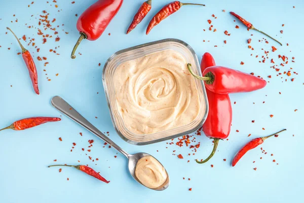 Bowl of tasty chipotle sauce and jalapeno peppers on color background