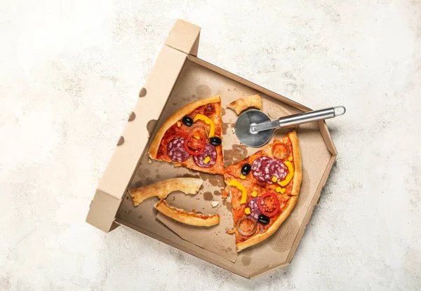 Cardboard box with tasty pizza and leftovers on light background