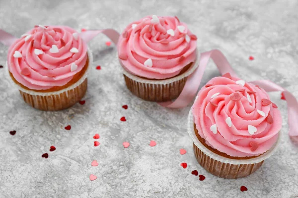 Arkaplanda Sevgililer Günü için kurdeleli ve kalpli lezzetli kekler.