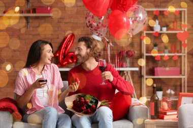 Sevgililer Günü 'nde evde şarap içen genç ve mutlu nişanlı çift.