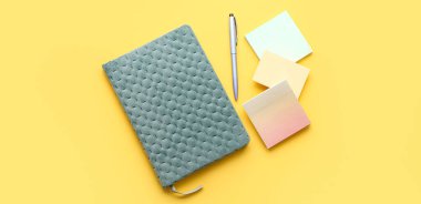 Sarı arkaplan, üst görünüm üzerine not defteri, kalem ve yapışkan notlar