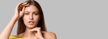 Gri arka planda kirpikleri olan, metin için yeri olan genç bir kadın.