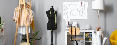 Terzinin dikiş makinesi, giysi askısı ve modern atölye mankeni.