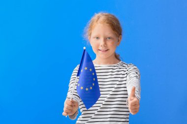 Avrupa Birliği bayrağı taşıyan küçük kız mavi arka planda baş parmak gösteriyor